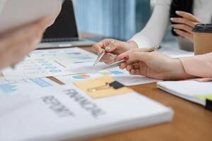 Diverse office workers collaborating on financial reports and strategy planning at a modern workspace. photo