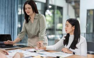 Diverse office workers collaborating in a meeting, discussing financial charts and strategies. photo