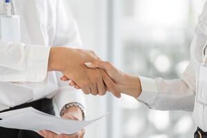 Professional handshake between colleagues discussing tax documents in an office setting. photo
