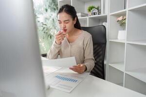 Office worker taking a moment to reflect while reviewing financial reports and data. photo