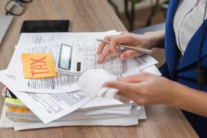 Accountant calculating taxes with a calculator amidst paperwork and receipts, focusing on financial details. photo