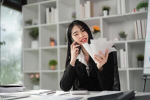 Happy accountant discussing finances on the phone while reviewing paperwork. photo