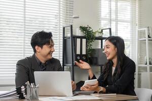 Diverse business partners smiling and discussing financial strategies in a modern office. photo