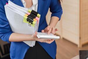 Accountant inputting data on calculator while holding tax documents photo