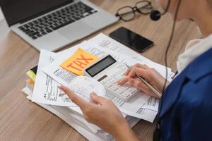 Accountant calculating taxes with a calculator and reviewing financial documents. photo