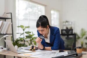 Accountant analyzing financial documents with a magnifying glass in a modern office setting. photo