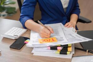 Accountant writing on tax documents with a calculator, preparing for financial filing. photo