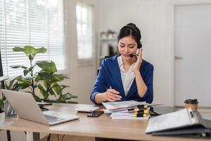 Accountant taking notes while on a call in a professional office environment. photo