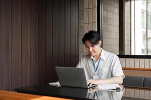 Young professional typing on laptop in modern office, demonstrating focus and commitment to work tasks. photo
