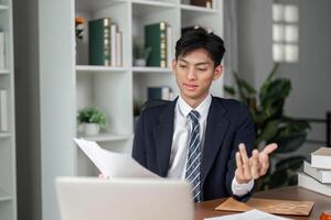 Young businessman explaining documents during a call in a modern office environment. photo