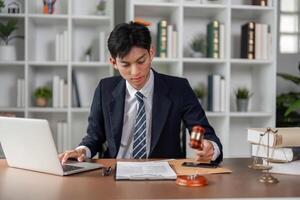 Young businessman using gavel to finalize decisions while reviewing documents in a modern office. photo