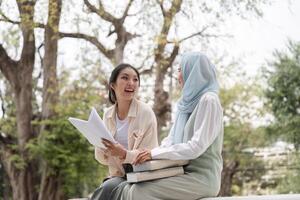 Diverse female students enjoying a discussion with books and notes in a university park setting. photo