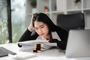 Overwhelmed accountant struggling with tax filings and financial paperwork at her office desk. photo
