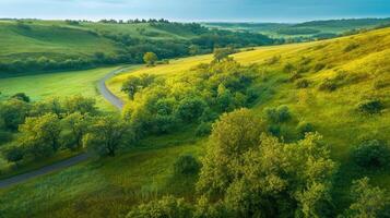 Tranquil landscape of rolling hills and green valleys with winding road and trees photo