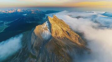 Majestic mountain peak emerging from clouds at sunrise in rugged terrain photo