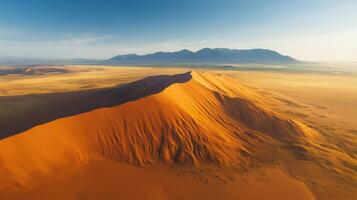 Aerial view of majestic sand dune in vast arid desert landscape under blue sky photo