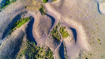 Aerial view of meandering path through arid sand dunes with sparse vegetation photo