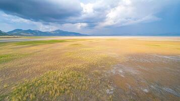 Expansive landscape with grass and mountains under cloudy sky, nature beauty photo