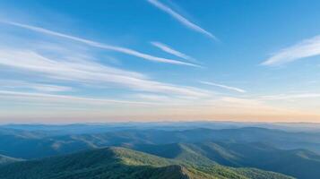 Expansive mountain range under clear sky with gentle clouds horizon view photo