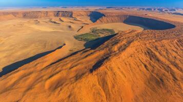 Aerial view of vast desert landscape with towering red sand dunes and central oasis photo
