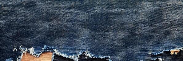 Frayed blue denim fabric close-up of worn textured material with unraveling edges photo