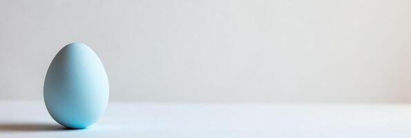 Minimalistic blue egg against soft white background for easter themes photo