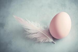 Pastel pink egg and feather on soft blue background as easter symbolism photo