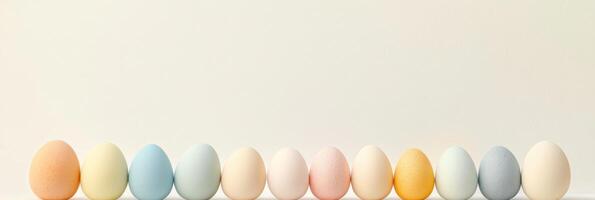 Assorted pastel-colored eggs in a row against neutral background photo