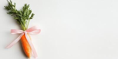 Fresh carrot with green leaves tied by a pink bow on a white background photo