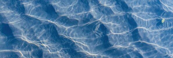 Sunlit water surface with rippling light patterns and textured shadows photo