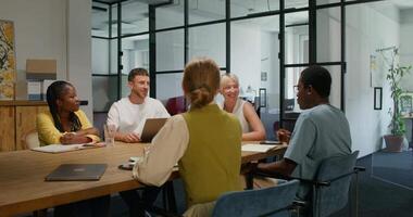 A group of people sitting around a table in an office video