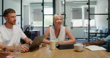 Three people sitting at a table with laptops video