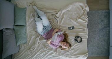 Top view of a woman lying on a bed with a tablet computer video