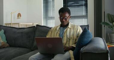 A man sitting on a couch using a laptop video