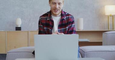 A man is sitting on a couch with a laptop video