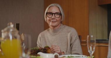 An older woman with glasses sitting at a table with food video