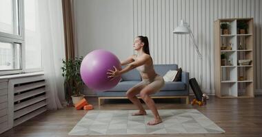 A woman is doing a squat with an exercise ball video