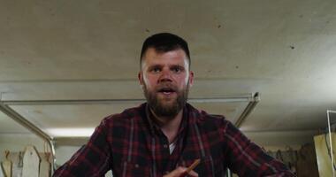 A man with a beard and a plaid shirt is making a sandwich video