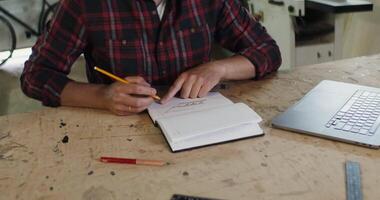 A man is writing in a notebook while sitting at a table video