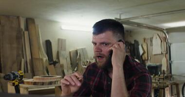 A man talking on the phone in a workshop video