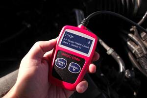 OBD or OBD-II scanner in use by technician , Automotive diagnostic tool in use for scanning fault code of car engine system , Car repair concept photo