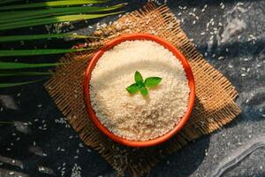 Bowl with uncooked rice and basil on the table, top view photo