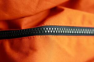 Zipper on the orange jacket. Close up view of zipper. photo