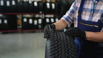 Worker checking tire tread depth with gauge tool video