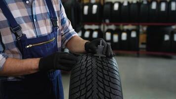 Worker measuring tire tread depth with gauge in store video