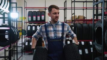 Tire shop worker carrying two tires for a customer video