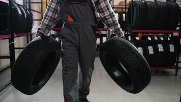 Tire shop worker carrying two tires for a customer order video
