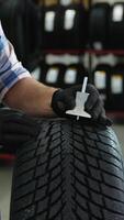 Tire store worker checking tread depth with gauge video