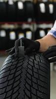 Worker checking tire tread depth with gauge tool video