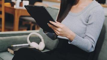 A woman sitting on a couch with a tablet computer video